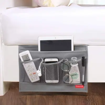 Durable charcoal felt bedside storage caddy tucked securely under mattress edge holding a book, smartphone, and glasses