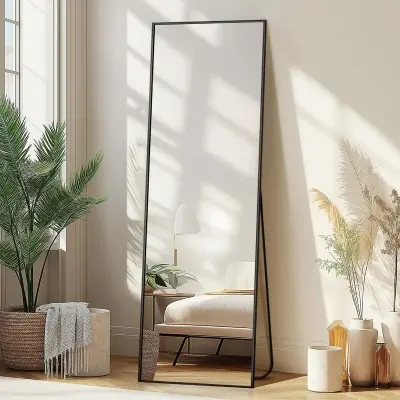 Arched full-length floor mirror with slim golden metal frame leaning gracefully in a bright airy modern bedroom corner