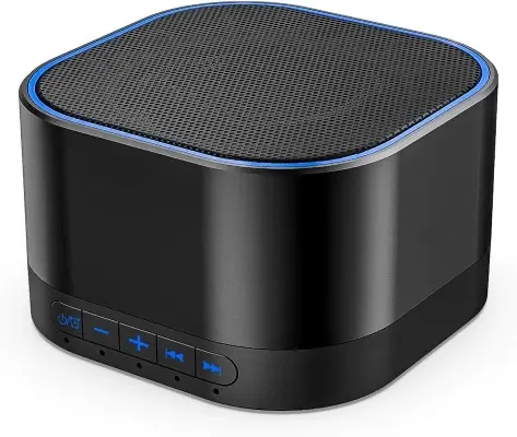 Modern compact white noise sound machine resting on a minimalist nightstand beside an open book and glass of water