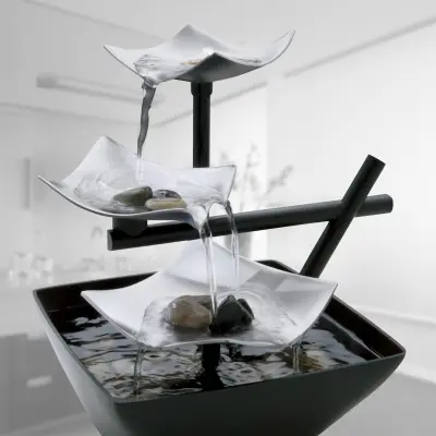Zen slate tabletop water fountain with smooth river stones and soft cascading water on a bedroom meditation table