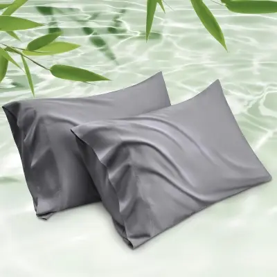 Silky breathable bamboo cooling pillowcases resting on crisp bed linen under soft bedroom reading lighting