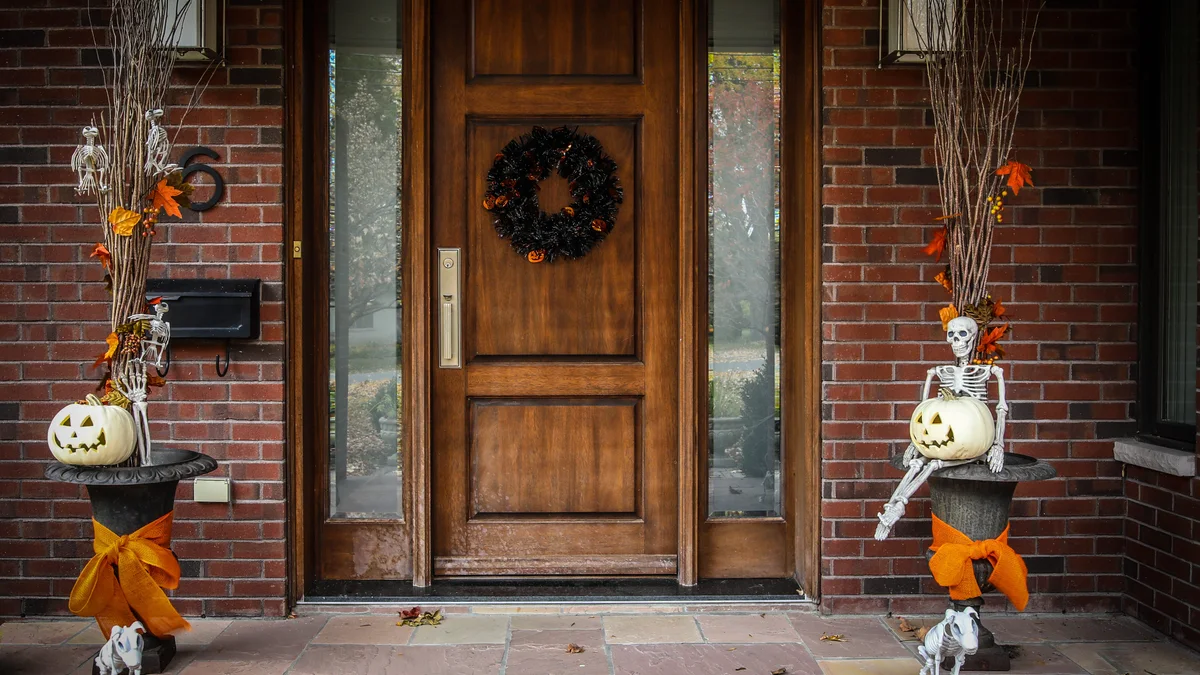 Stone front steps lined with varying heights of bronze and glass lanterns glowing warmly alongside carved pumpkins
