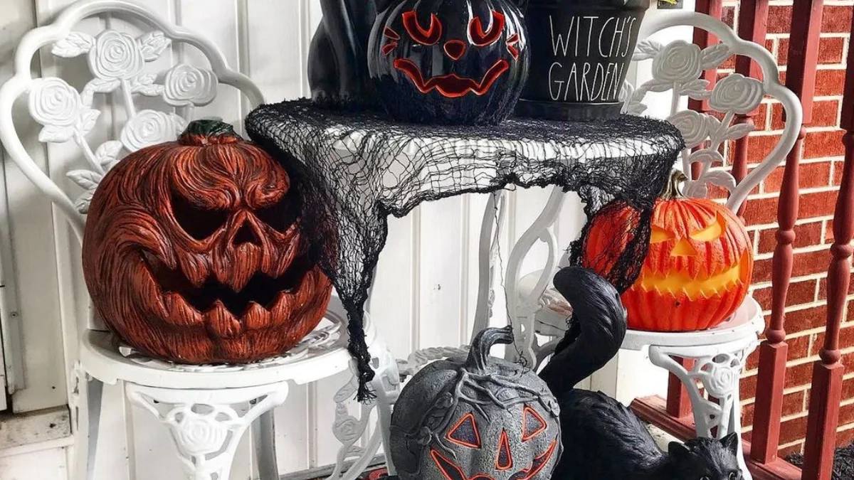 Tasteful outdoor patio vignette showcasing black ceramic cats, terracotta pumpkins, and wrought iron chairs in charcoal and rust