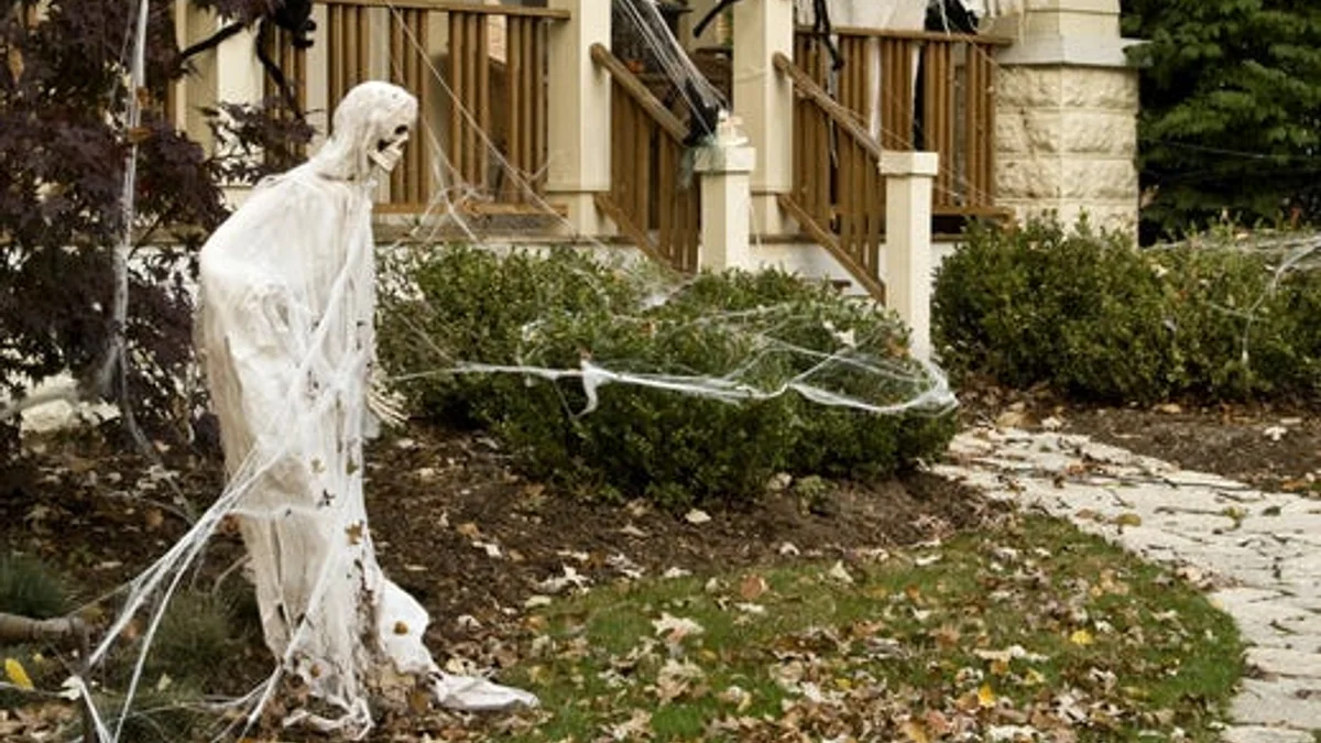 Front porch pillars draped in shredded white cheesecloth and gossamer cotton webbing with subtle dark spider silhouettes