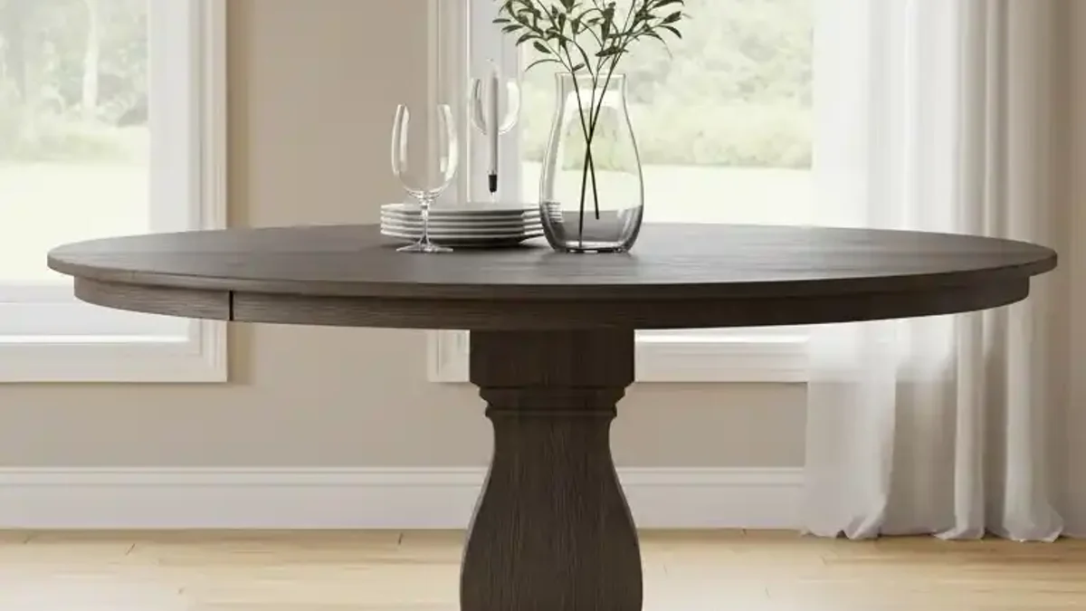 Round wooden pedestal dining table in a bright small dining room