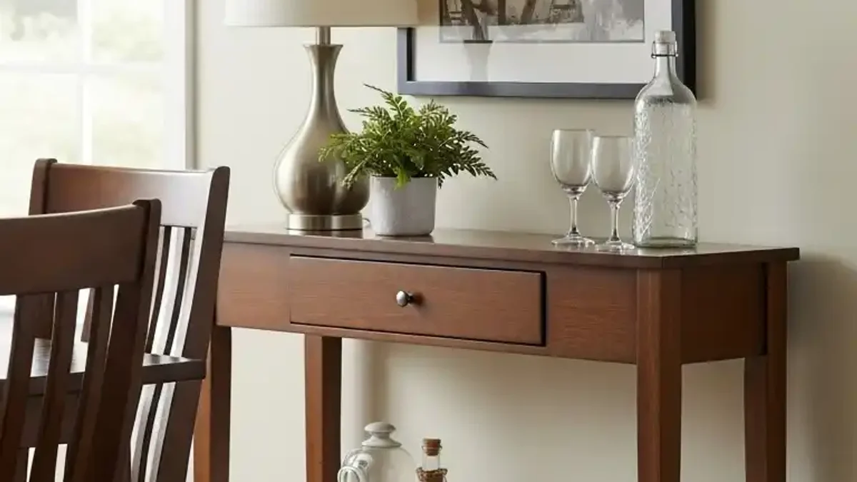 Slim console table with warm ambient lamp and candle glow beside a tiny dining area