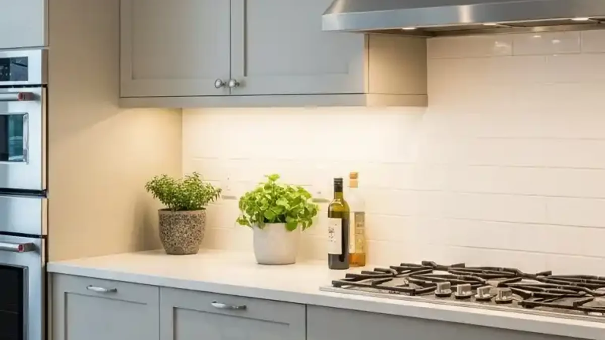 Cozy built-in kitchen coffee bar nook illuminated by dedicated warm under-cabinet lighting above an espresso machine
